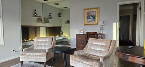 A living room with two striped armchairs, a small round table, a wooden cabinet, and a framed picture on the wall. - Charming Home In Quiet, Friendly Grangeville, Idaho Sleeps 9 Guests (Grangeville)