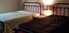A bedroom with two beds, a nightstand with a lamp, and a digital clock. - Charming Home In Quiet, Friendly Grangeville, Idaho Sleeps 9 Guests (Grangeville)