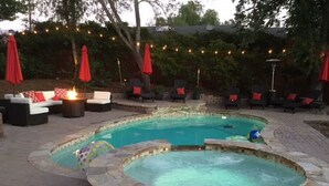 A backyard with a hot tub and a pool, surrounded by outdoor seating and string lights. - Adorable 4 Bedroom Guest House wPool + Jacuzzi (Poway)