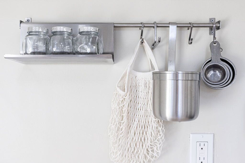 A kitchen with a hanging rack holding jars and a pot.