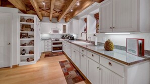 A kitchen with white cabinets, a wooden ceiling, and a granite countertop.