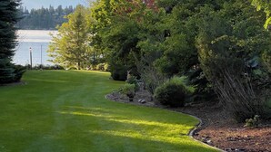 A well-maintained grassy area with trees and a view of a body of water.