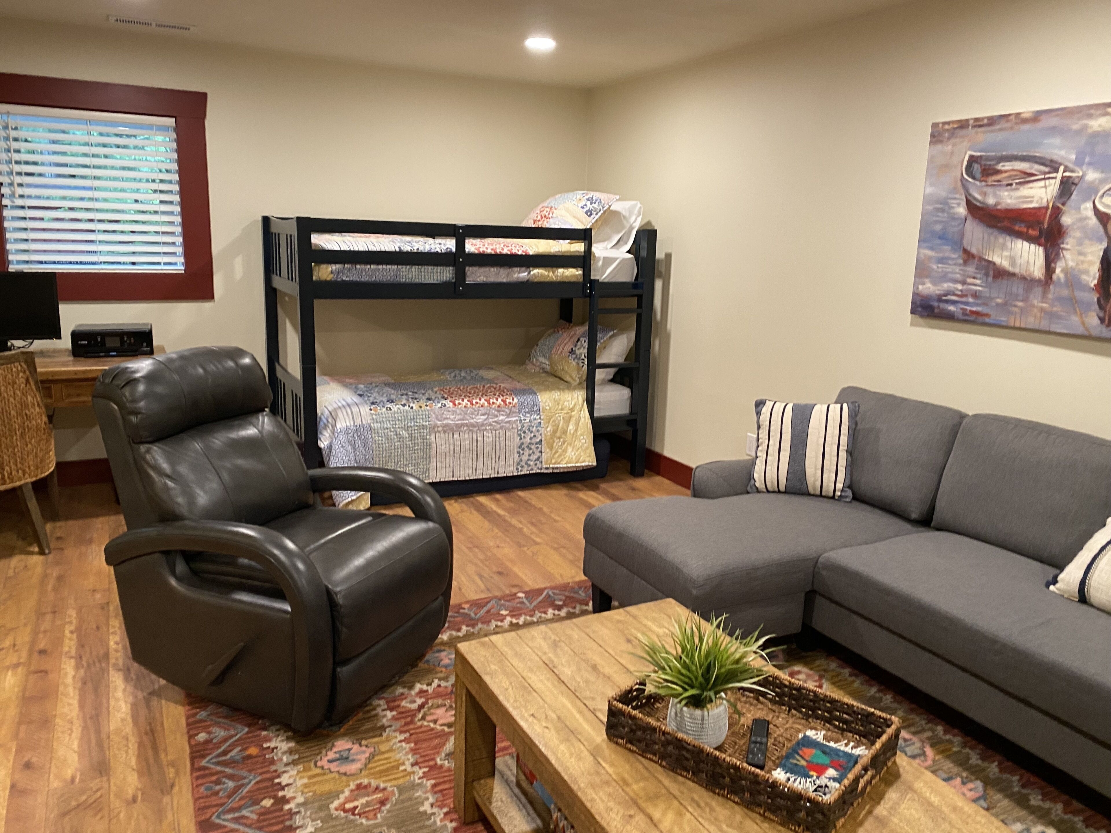 Una habitación amoblada con una cama doble, un sillón de cuero, un sofá, una mesa de centro con una planta y un televisor.