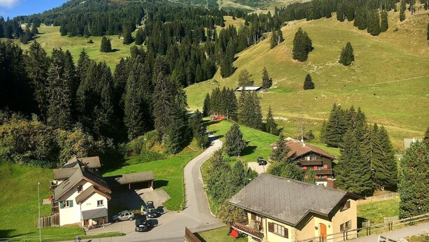 A mountain village with a winding road, houses, and a prominent mountain in the background. - Bellavista 4 by Interhome (Parpan)