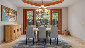 Un coin repas avec une table en bois, six chaises et un lustre.