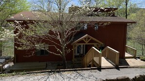 A red wooden cabin with a wooden staircase leading to a porch. - Luxury Norris Lake Getaway - Perfect for Families & Groups - Lake Front w Dock! (Caryville)