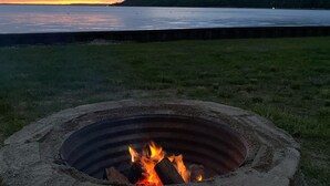 A fire pit with a view of a lake and a cloudy sky at dusk. - Amazing waterfront and sunset views! (Indian River)