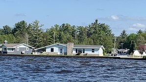 A waterfront property with multiple small houses, a dock, and a forested background. - Amazing waterfront and sunset views! (Indian River)