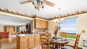 A kitchen with wooden cabinets, a dining table with chairs, and a view of the ocean. - Amazing waterfront and sunset views! (Indian River)