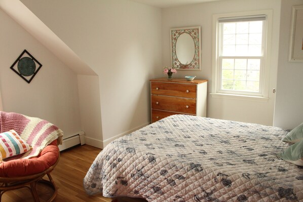 A bedroom with a bed, a dresser, a chair, and a window.