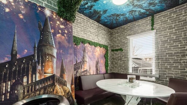 A room with a round table, dark brown seating, a brick wall, and a mural of a castle. - ★McGonagall’s Mansion ★ Private Home w/ Arcade★ (Columbus)