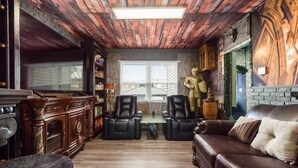 A room with a wooden ceiling, a brown leather sofa, two black leather chairs, a small table, and a brick wall with a statue. - ★McGonagall’s Mansion ★ Private Home w/ Arcade★ (Columbus)