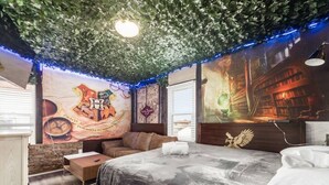 A bedroom with a bed, a wooden nightstand, a brown leather sofa, and a wall mural. - ★McGonagall’s Mansion ★ Private Home w/ Arcade★ (Columbus)