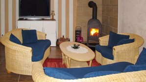 Una sala de estar con dos sofás de mimbre, un televisor de pantalla plana, una chimenea y una mesita.