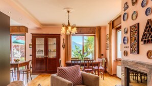 Amplia sala de estar con chimenea, muebles de madera y comedor con vistas al exterior.