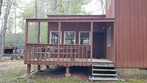 Une cabane en bois dotée d’un porche et d’une porte donnant sur l’intérieur.