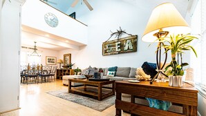 Un salon spacieux avec une table basse en bois, un canapé et une lampe. On y trouve également un coin repas avec des chaises et un lustre.