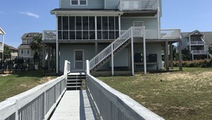 A two-story building with a balcony and a wooden walkway leading to the entrance. - Amazing  Intercostal Waterway Home at Holden Beach (Holden Beach)
