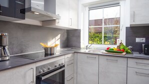 Una cocina moderna con horno integrado, cafetera y ventana con vistas a zonas verdes.