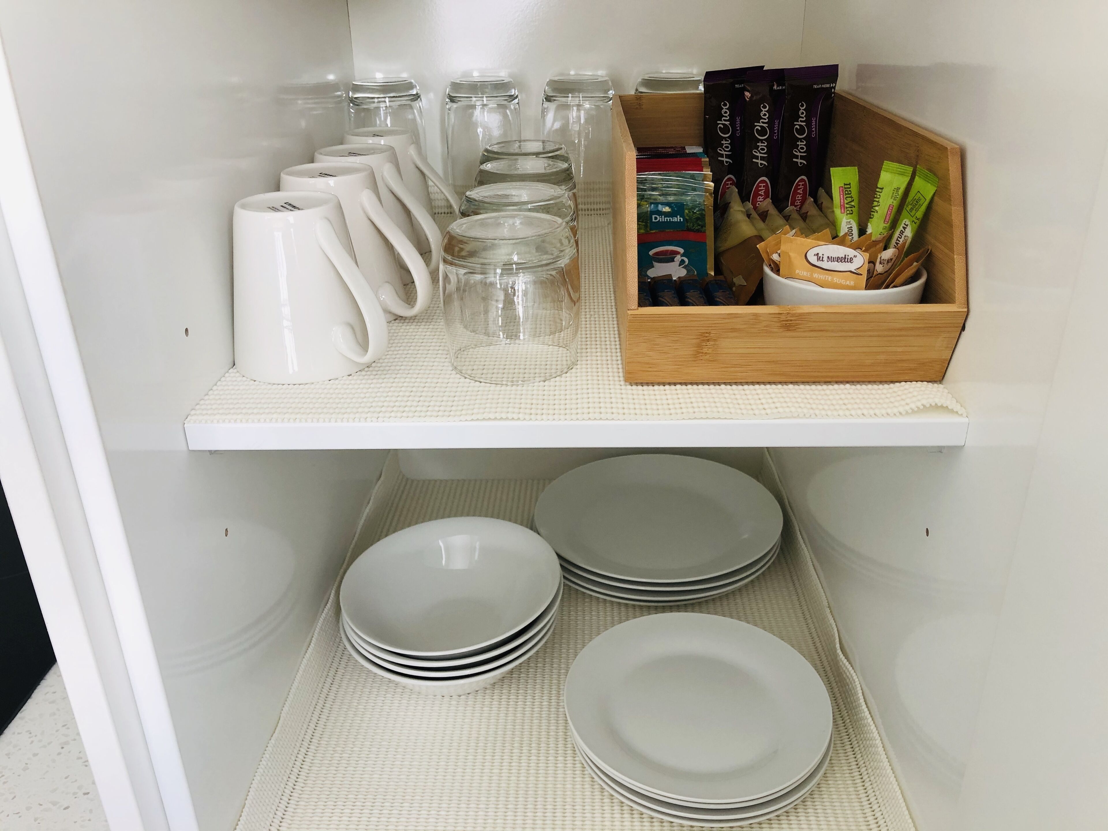 A kitchen shelf with jars, a coffee maker, and a box of tea bags.