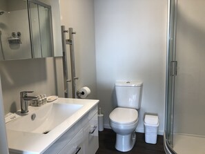 A modern bathroom with a white sink, toilet, and shower. - Central Stadium Apartments (Hamilton)