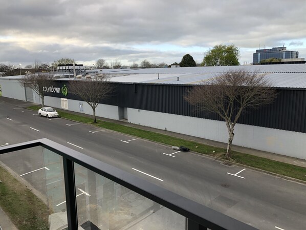A parking lot with a white car, a building with a black facade, and a clear sky. - Central Stadium Apartments (Hamilton)