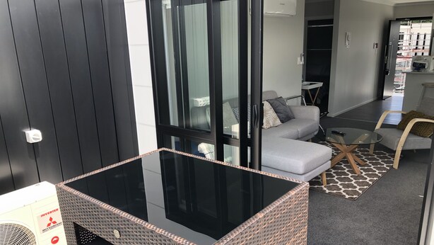 Un salon moderne avec une table basse en verre, un canapé gris et un tapis à motifs.