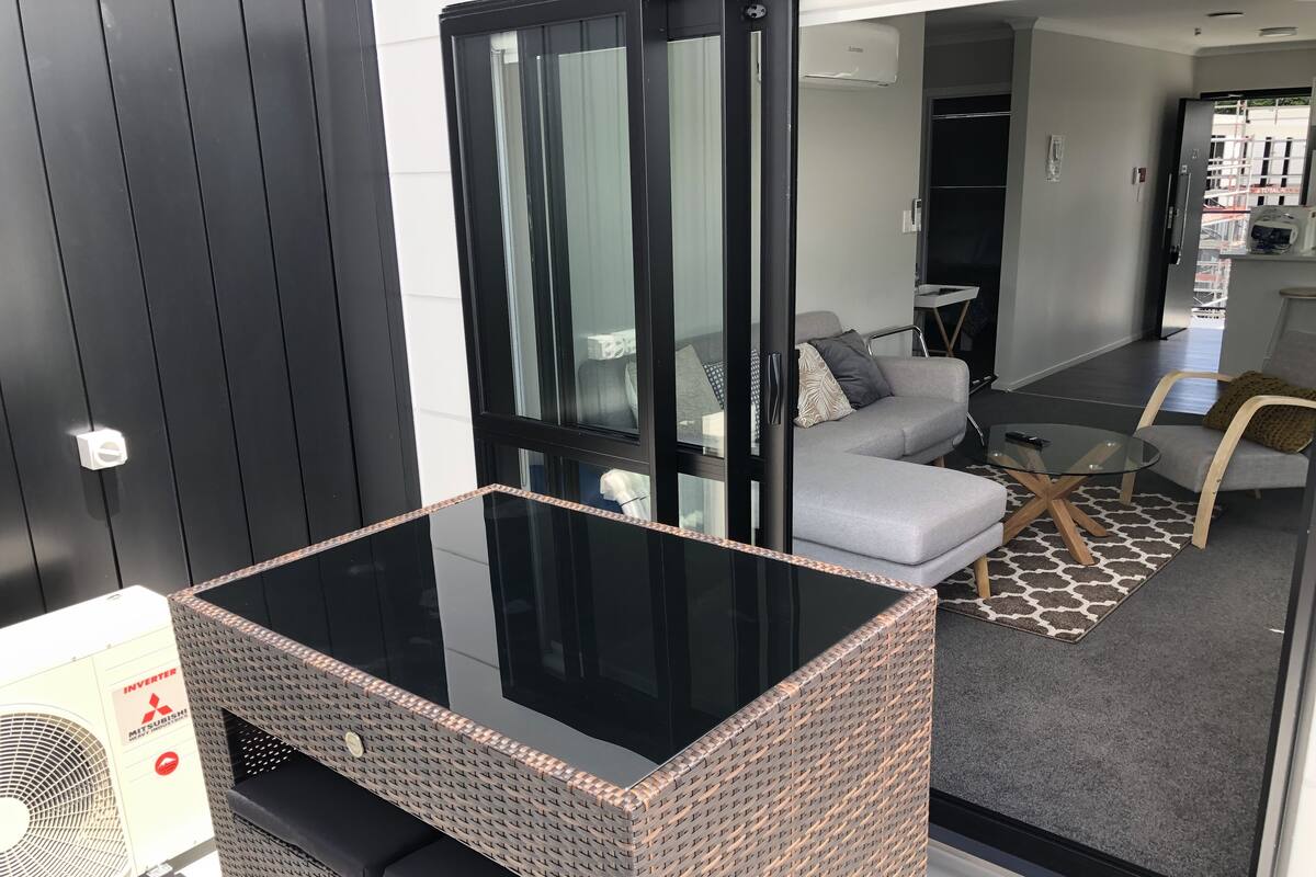 Una sala de estar moderna con una mesa de centro de vidrio, un sofá gris y una alfombra estampada.