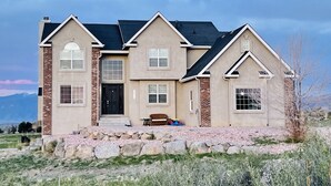 A two-story house with a stone foundation, multiple windows, and a front porch. - Massive Spacious House with Views, Adventure and Location (Colorado Springs)