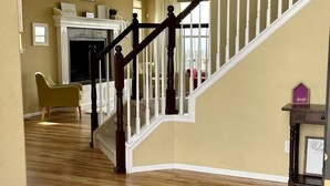 A spacious living area with a wooden staircase, a fireplace, and a view of the backyard. - Massive Spacious House with Views, Adventure and Location (Colorado Springs)