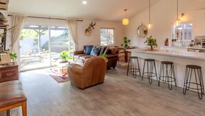 A spacious living area with a sofa, a coffee table, and a dining table with bar stools.