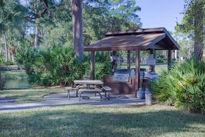A gazebo with a grill and picnic table in a park setting. - Villa on Quiet Cul-De-Sac | Heated Pool and Spa (Sarasota)