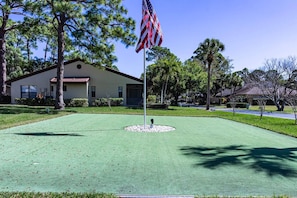 A well-maintained lawn with a flagpole and a building in the background. - Villa on Quiet Cul-De-Sac | Heated Pool and Spa (Sarasota)