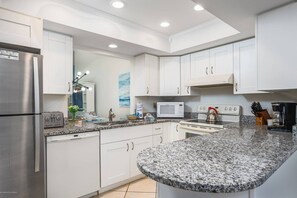 A modern kitchen with white cabinetry, granite countertops, stainless steel appliances, and a central island. - Villa on Quiet Cul-De-Sac | Heated Pool and Spa (Sarasota)