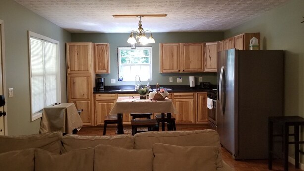 A kitchen with wooden cabinets, a dining table, and a refrigerator.