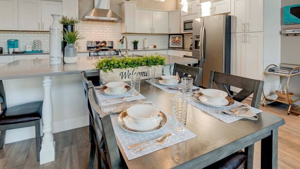 A modern kitchen with white cabinetry, a central island, and a dining area set for four. - Sleeps 12~Great View! UNR~Deck~Reno~Minerva House~ Near Downtown~Family Fun (Reno)