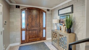 A wooden double door with glass panels, a console table with a lamp, and a framed picture on the wall. - Sleeps 12~Great View! UNR~Deck~Reno~Minerva House~ Near Downtown~Family Fun (Reno)