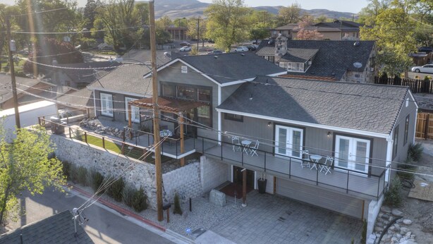 A two-story house with a balcony, a stone wall, and a driveway. - Sleeps 23~Downtown~Historic Stone Minerva Estate (Reno)