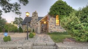 Ein Steinhaus mit einer Steintreppe, die zum Eingang führt, einer amerikanischen Flagge und einem gepflegten Garten.