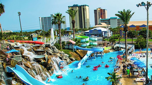 A water park with multiple water slides and pools, surrounded by palm trees and buildings. - 🌊Private Fenced in Pool~Steps 2 Beach~Huge Home~5BR Stella di Mare🌅 (Destin)