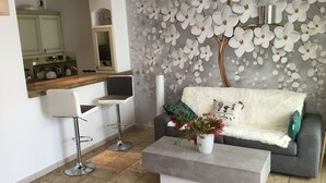 A modern living room with a grey sofa, a white coffee table, and a bar area with a mirror and stools. - Mistral Gagnant (Fréjus)