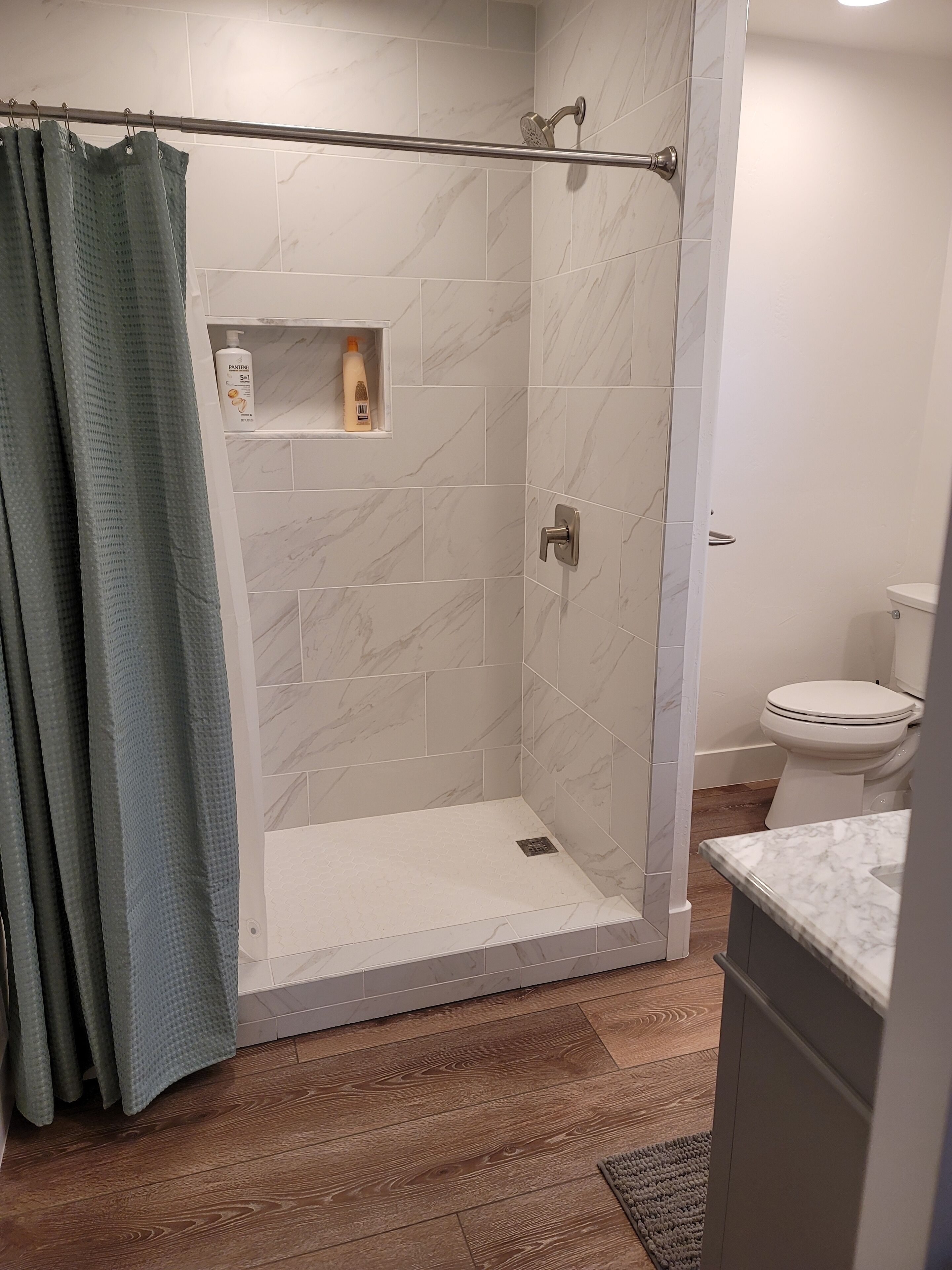 Une salle de bain moderne comprenant un espace douche, des toilettes et un meuble-lavabo avec un plan de travail en marbre.