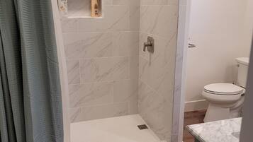 Une salle de bain moderne comprenant un espace douche, des toilettes et un meuble-lavabo avec un plan de travail en marbre.