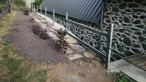 Un chemin menant à un bâtiment en pierre surmonté d’un toit en métal.