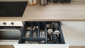 A kitchen with a black stovetop, a stainless steel kettle, and wooden utensils on the counter.