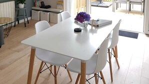 A modern kitchen with a white table and chairs, a clock on the wall, and a sliding glass door leading to an outdoor patio.