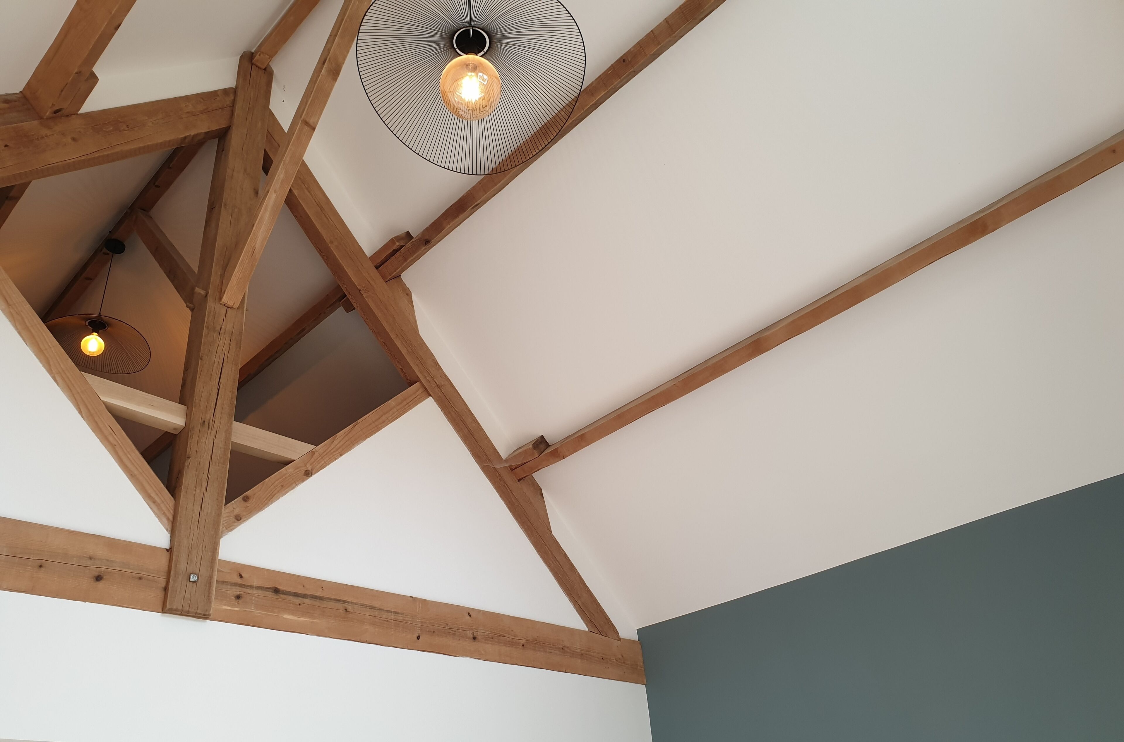 A ceiling with exposed wooden beams and two pendant lights.