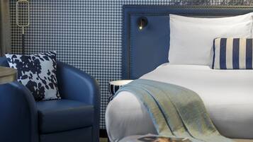 A bedroom with a bed, a chair, a lamp, and a framed picture on the wall.