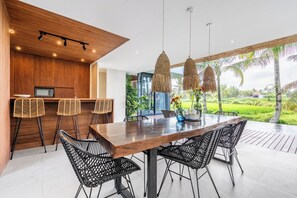 Cocina moderna con armarios de madera, microondas integrado y una zona de bar con sillas de mimbre.