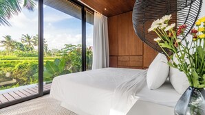 A bedroom with a large window, white bedding, and a vase with flowers. - Green Flow Villa 20 (Ubud)